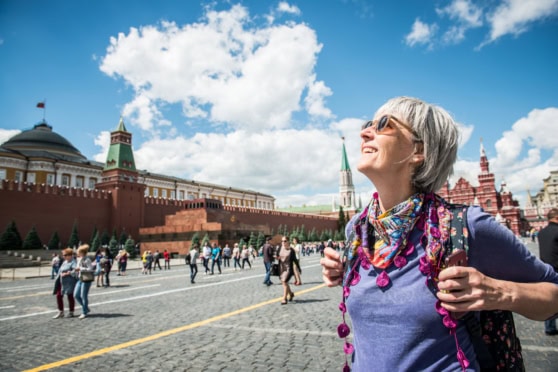 An elderly woman enjoying sightseeing in Moscow, Russia, with iconic landmarks and a clear, sunny sky, highlighting international travel protection.