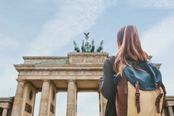 People exploring Berlin with backpacks near the historic Brandenburg Gate, a symbol of unity.