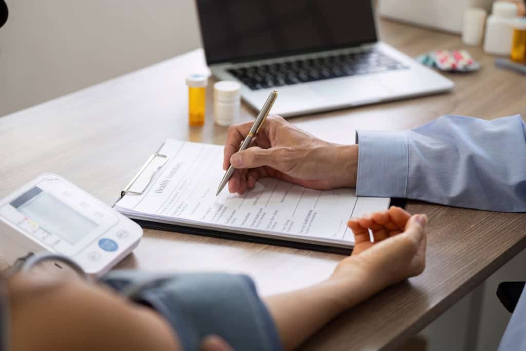 Medical professional completing full medical underwriting paperwork for international health insurance with pre-existing conditions