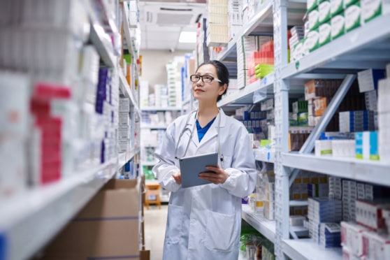 A healthcare professional inspecting pharmaceutical supplies in a pharmacy aisle, highlighting the importance of reliable international health coverage.