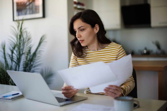 A woman reviews medical documents at home, emphasizing international health insurance plans for global citizens, ensuring comprehensive coverage worldwide.