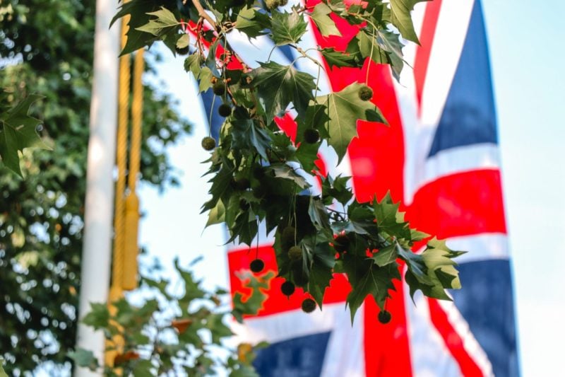 Life for expats in the UK: A British flag flies in the background with green leaves in the forground