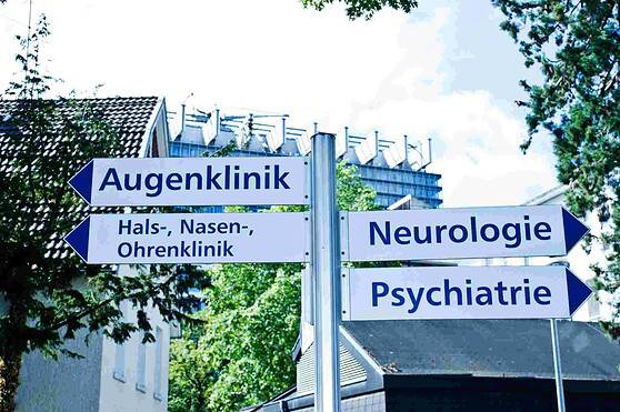 An image showing directional signs pointing to various medical clinics such as eye, ENT, neurology, and psychiatry, set against a backdrop of trees and buildings, representing healthcare and medical services.