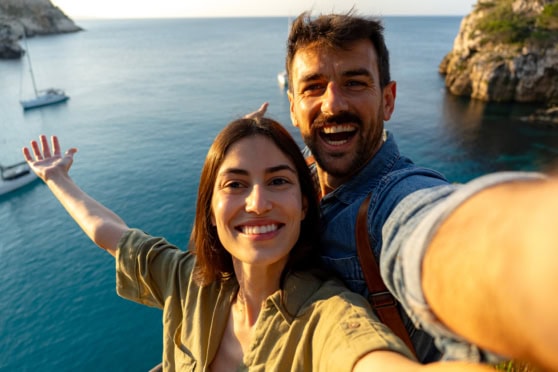 Image of a happy couple taking a selfie near the sea, showcasing travel and adventure.