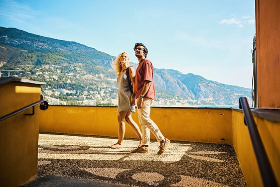 Young couple enjoying sunny day outdoors with scenic mountain view.