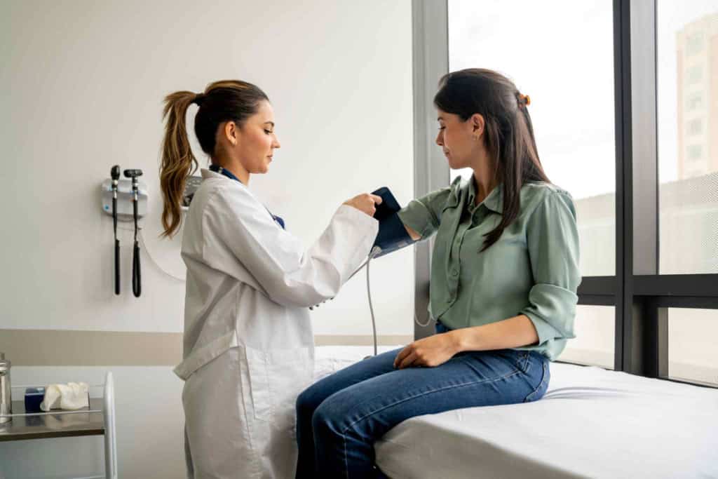 patient receiving healthcare in France, with doctor checking her blood pressure
