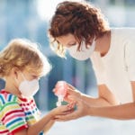 Mother and child wearing masks with hand sanitizer