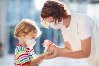 Mother and child wearing masks with hand sanitizer