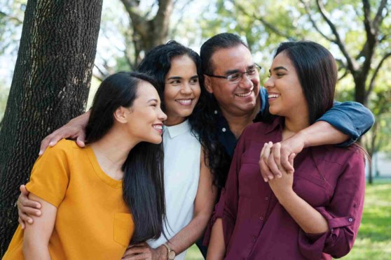 Happy multicultural family hugging outdoors, illustrating global health coverage benefits for international travelers and expatriates.