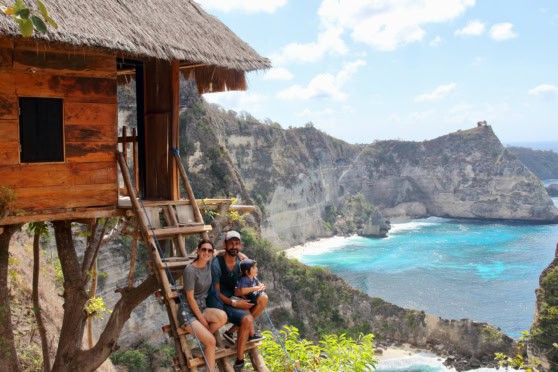 Family relaxing at a treehouse overlooking cliffs and turquoise sea during travel adventure.