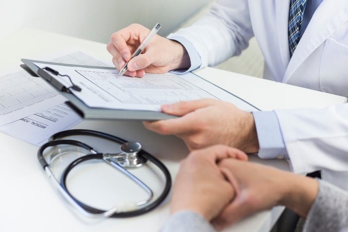 doctor taking notes stethoscope on table