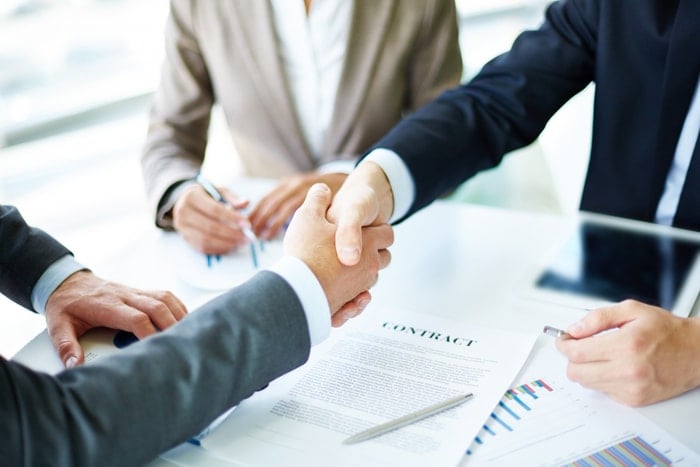 shaking hands over documents on table