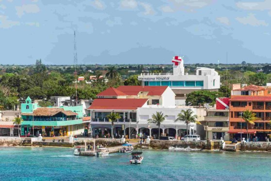 This image highlights a picturesque coastal town perfect for international travelers, with vibrant waterfront, lush greenery, and healthcare facilities, emphasizing global health and travel insurance needs.