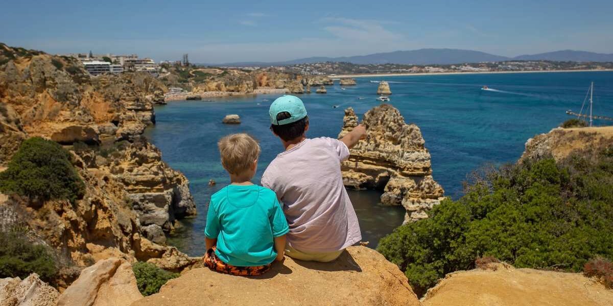 two children sitting facing the sea in Portugal, which many Americans consider the best country to move to from usa with family