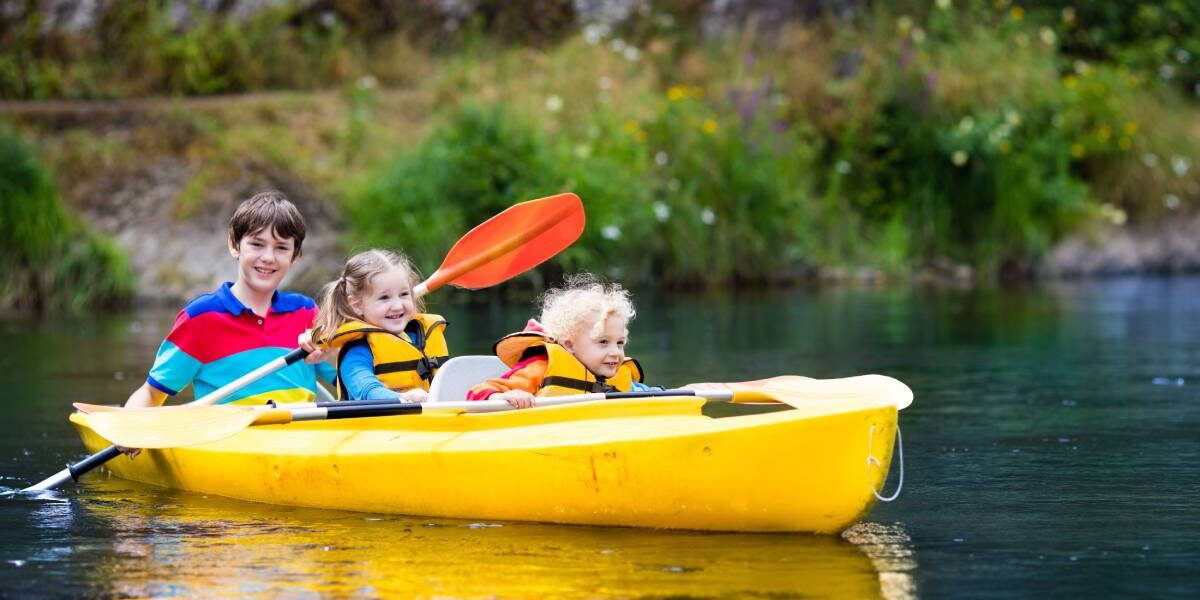 three children sitting in a kayak on a lake in Canada