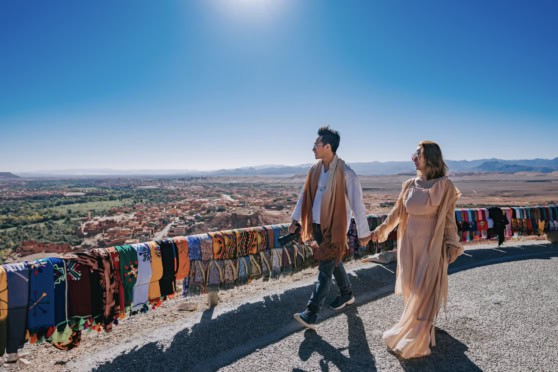 Travelers in traditional attire enjoying scenic vistas in a desert landscape, with vibrant textiles adding cultural richness, representing global mobility and international experiences.