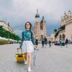 a woman pulling a suitcase behind her in a city, indicating the process of becoming an expat