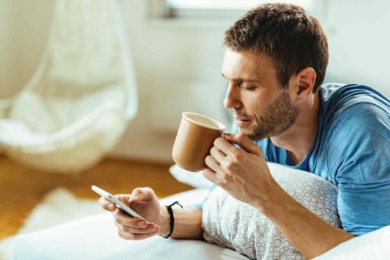 A man enjoying a coffee while using his smartphone, symbolizing international travel and expatriate lifestyle with emphasis on global insurance coverage.