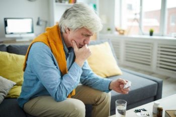 Older gray-haired man reading pill bottle