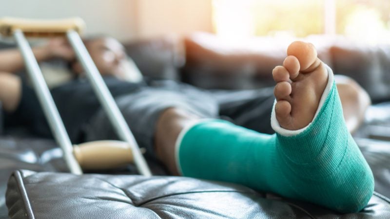 man with broken leg propped on footstool