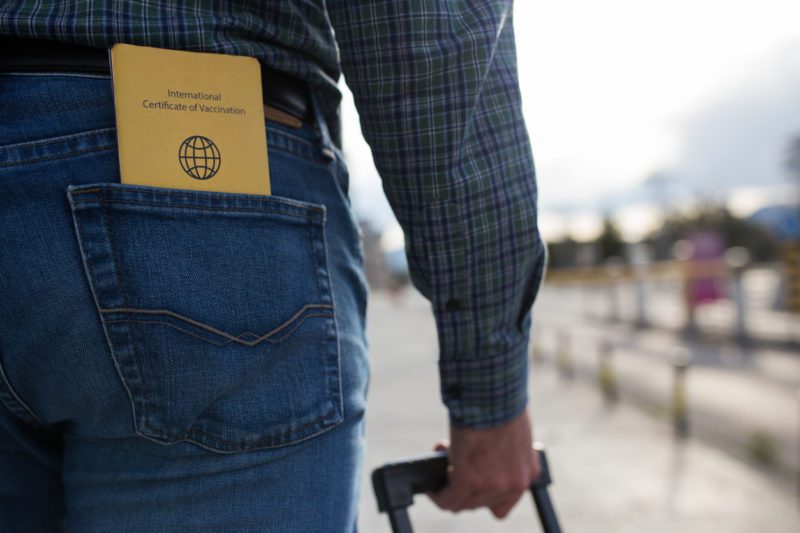 Traveler with international vaccine record in back pocket of jeans