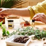 An alternative medicine practitioner's hands across a table with herbs, oils, and other commonly used products in alternative medicine.