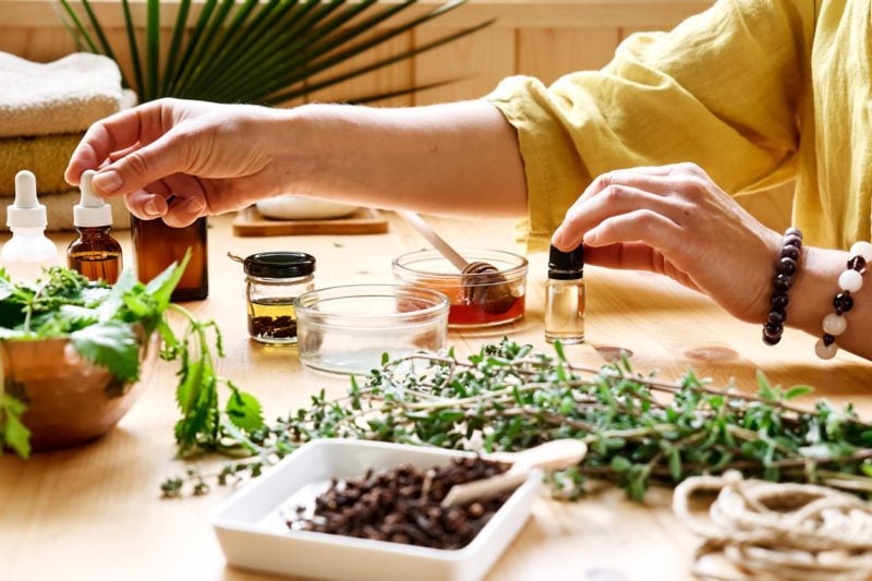 An alternative medicine practitioner's hands across a table with herbs, oils, and other commonly used products in alternative medicine.