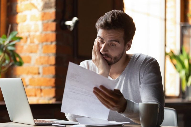 Man at laptop with letter saying his health insurance claim is rejected