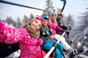 Happy family with winter travel insurance on a ski lift