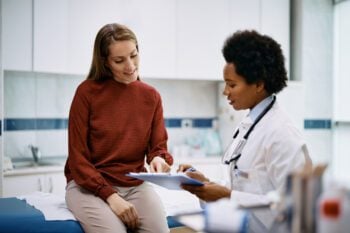 African American doctor and her female patient analyzing medical report after examination in the hospital. 