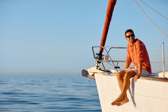 Sailor relaxing on a yacht in the open sea, enjoying sunny weather and blue skies, ideal for nautical activities and marine leisure.