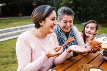 health-insurance-greek-expats two Greek women and a young girl preparing food outside having secured health insurance for Greek expats