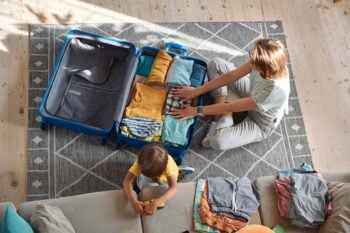 packing-for-vacation an aerial view of a blonde woman packing a suitcase for her child, having bought travel insurance for Hungarian citizens