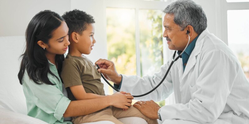 a doctor performing a medical checkup of a little boy, indicating the need to find a doctor abroad