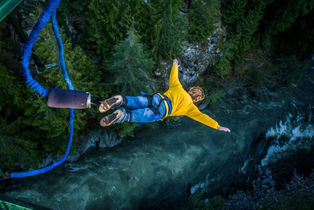 a traveler bungee jumping over a lake, indicating the need for adventure travel insurance