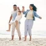 a family smiling and holding hands on a beach, knowing they are protected by