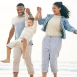 a family smiling and holding hands on a beach, knowing they are protected by