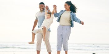 a family smiling and holding hands on a beach, knowing they are protected by