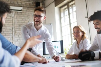 Group of people sitting around a table with a man talking.