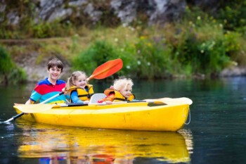 three children in a kayak on a lake in Canada, one of the best countries to move to from the USA with family