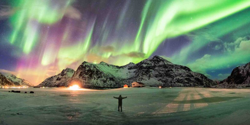 a tourist watching the Northern Lights, indicating one of the major travel trends in 2025