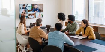 a team engaging with remote colleagues via a large screen, illustrating the advantage of partnering with an international PEO to hire and manage global talent seamlessly