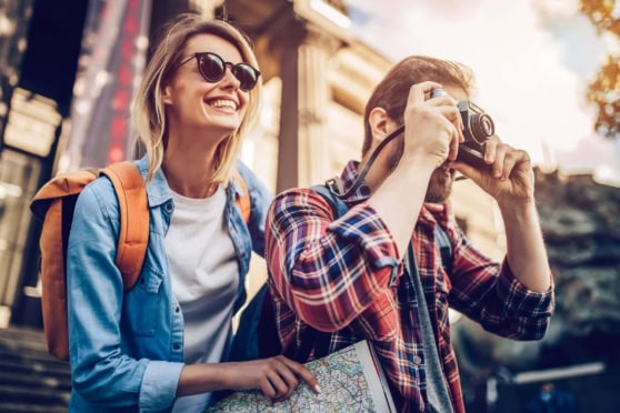 Young couple sightseeing in urban area, woman smiling and man taking photos, travel and tourism concept.