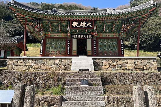 Beautiful Korean temple showcasing intricate woodwork and vibrant colors, set against lush greenery and a clear blue sky, representing cultural heritage.