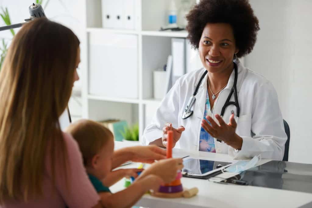 Medical consultation with a doctor, mother, and child in a healthcare setting, emphasizing international medical insurance for families living or traveling overseas.