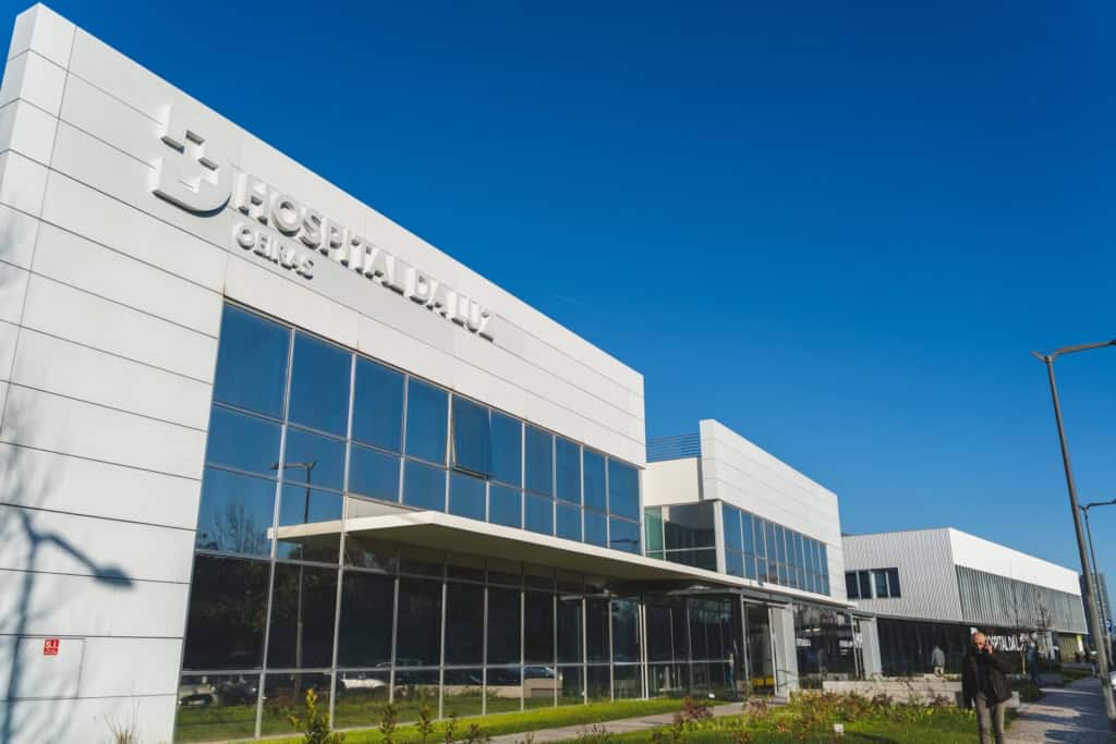 Modern hospital building with large glass windows and white exterior, representing advanced healthcare facilities.