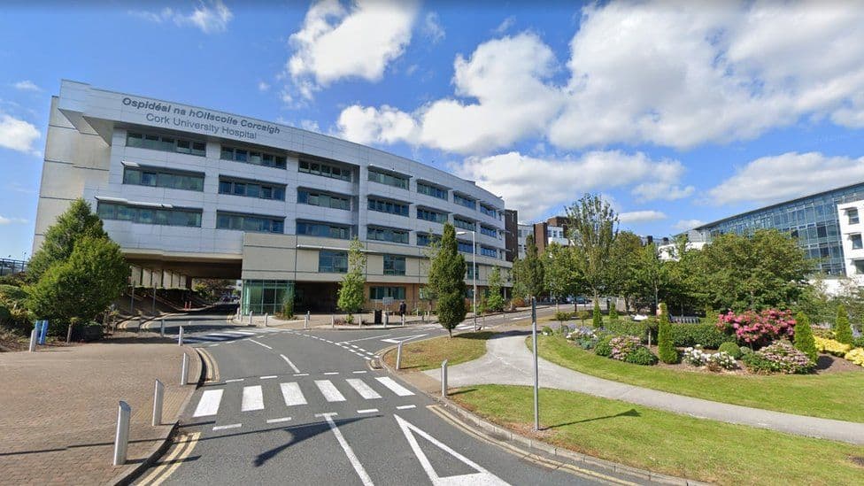 A modern hospital building with a landscaped garden and clear road signs, representing quality international health insurance options for global citizens.