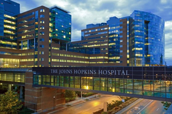 Hospital building at dusk with illuminated windows, glass exterior, and modern architecture, representing top-quality healthcare services and medical innovation.