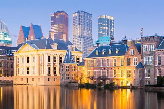 Bright city skyline featuring historic and modern buildings along a peaceful river at sunset, illustrating international urban allure and vibrant architecture.