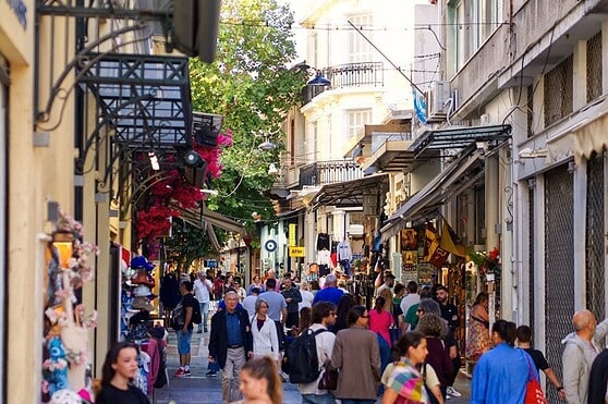 Bright city street lively with pedestrians, storefronts, and outdoor cafes, capturing urban life and international culture.
